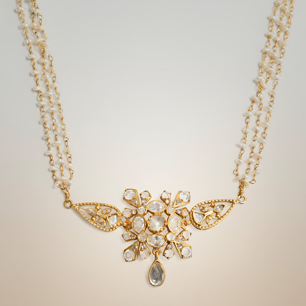 Pearl choker necklace with gold plated silver and stone pendant on a light background