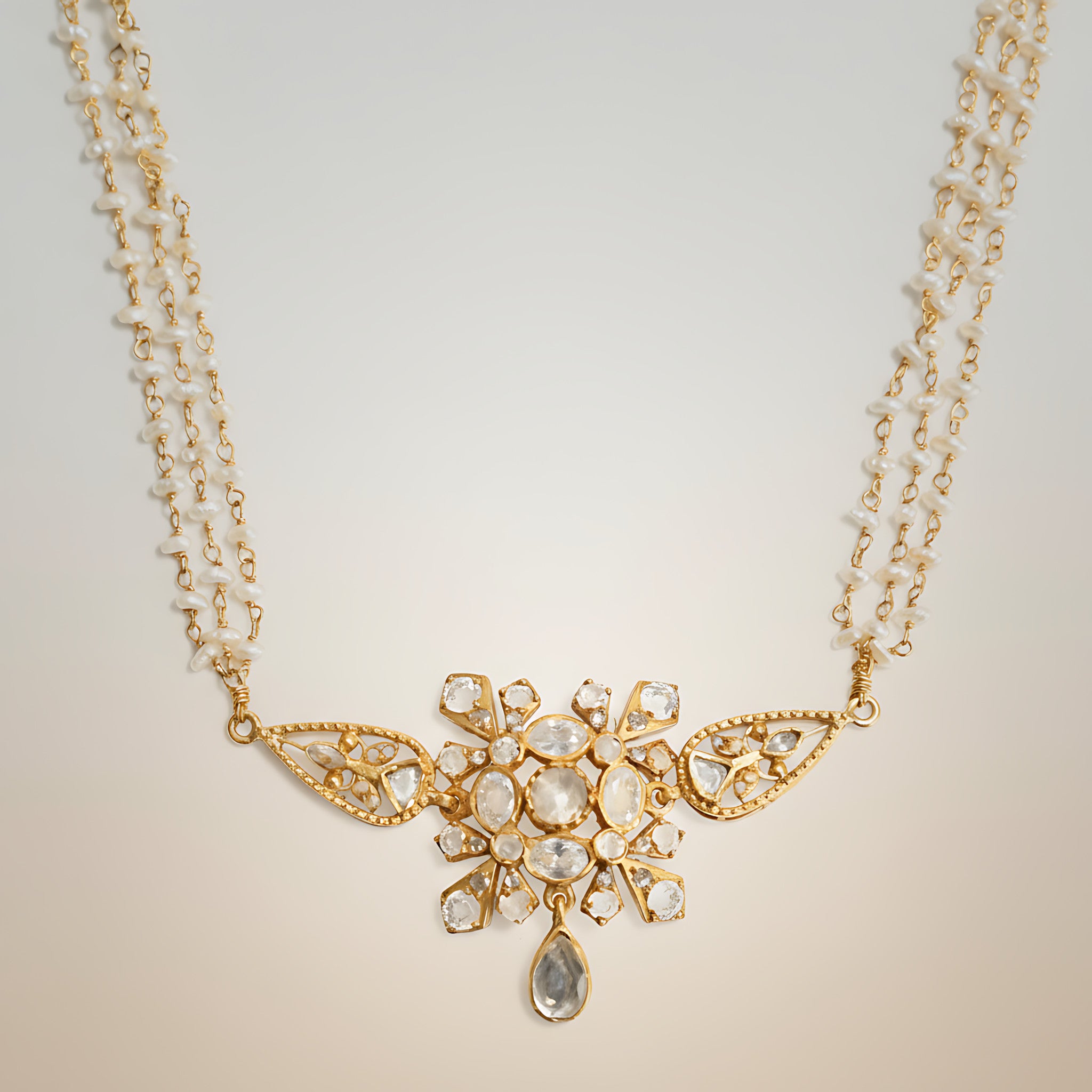 Pearl choker necklace with gold plated silver and stone pendant on a light background