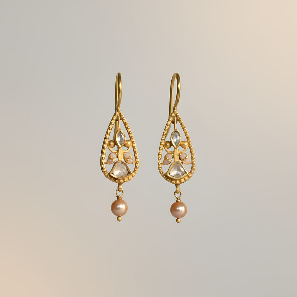 Gold plated silver earrings with pearl drops and stones on a light gray background