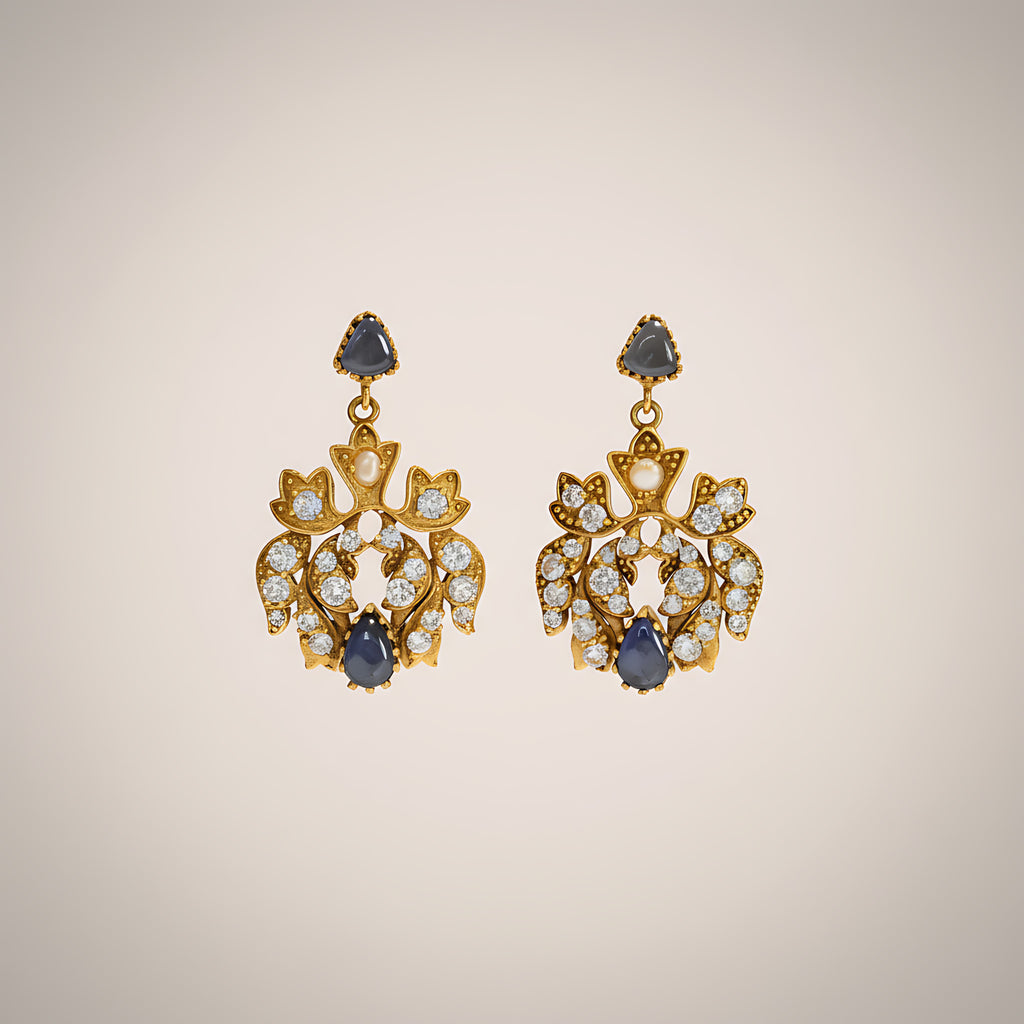Pair of gold plated silver earrings with blue gemstones on a beige background