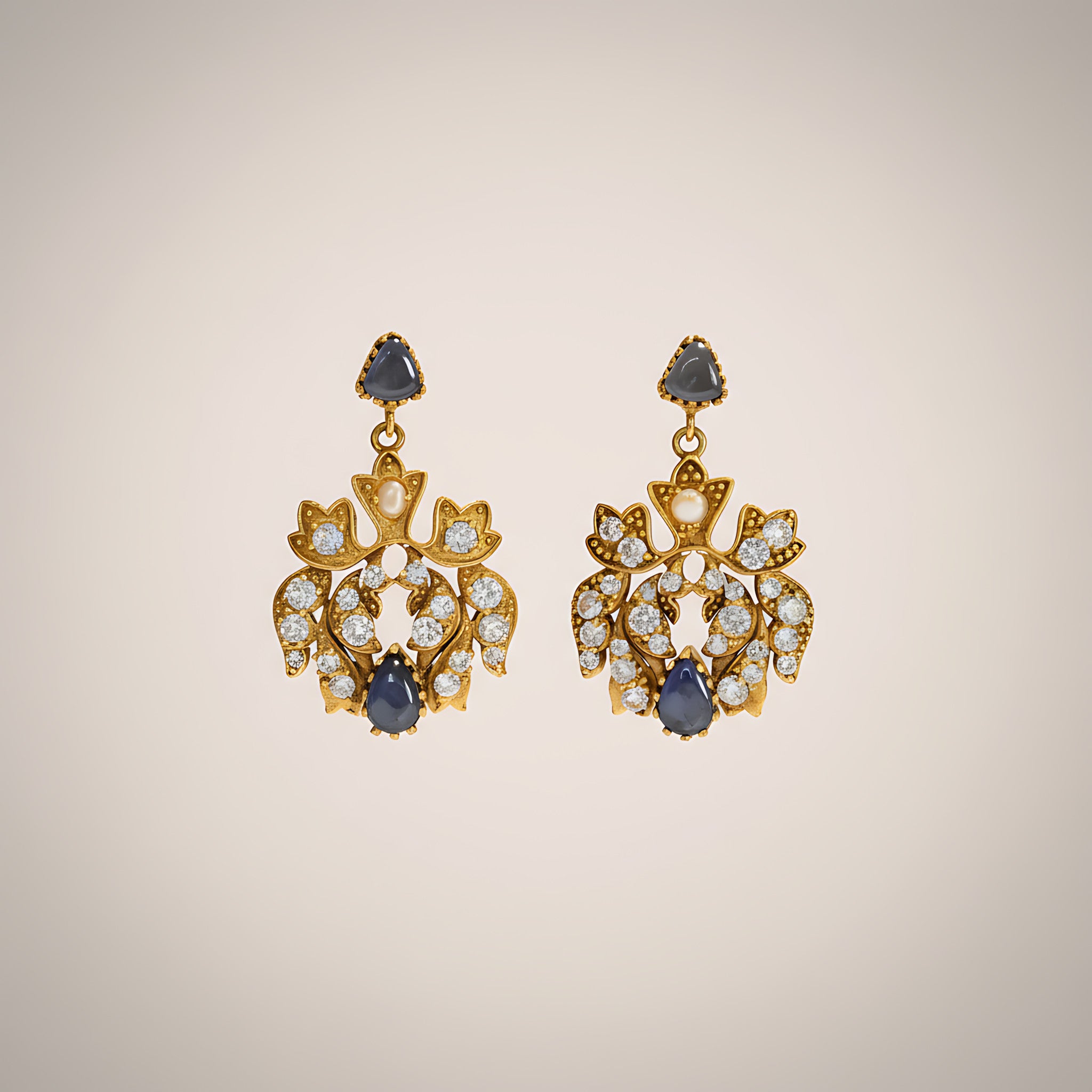 Pair of gold plated silver earrings with blue gemstones on a beige background