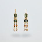 Pair of gold plated silver earrings with green gemstones on a light gray background