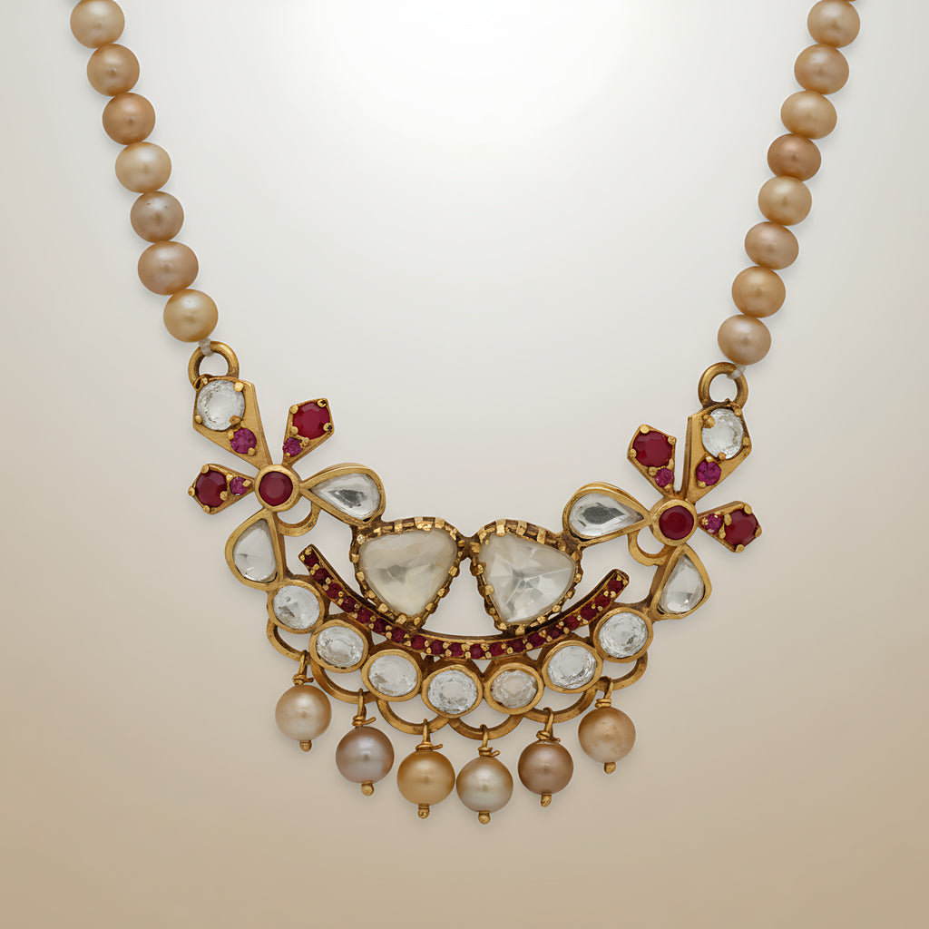 Pearl necklace with a decorative gold plated silver and gemstone pendant on a beige background