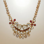 Pearl necklace with a decorative gold plated silver and gemstone pendant on a beige background
