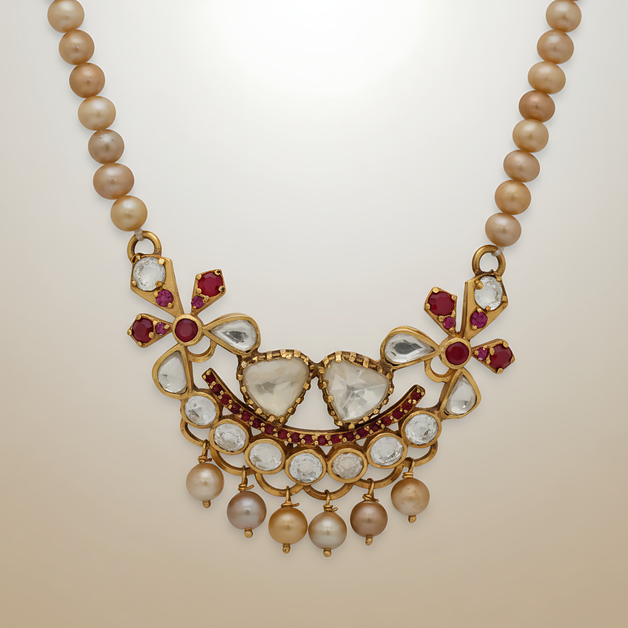 Pearl necklace with a decorative gold plated silver and gemstone pendant on a beige background