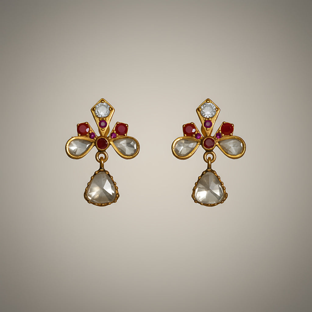 Pair of gold plated silver earrings with gemstones on a beige background