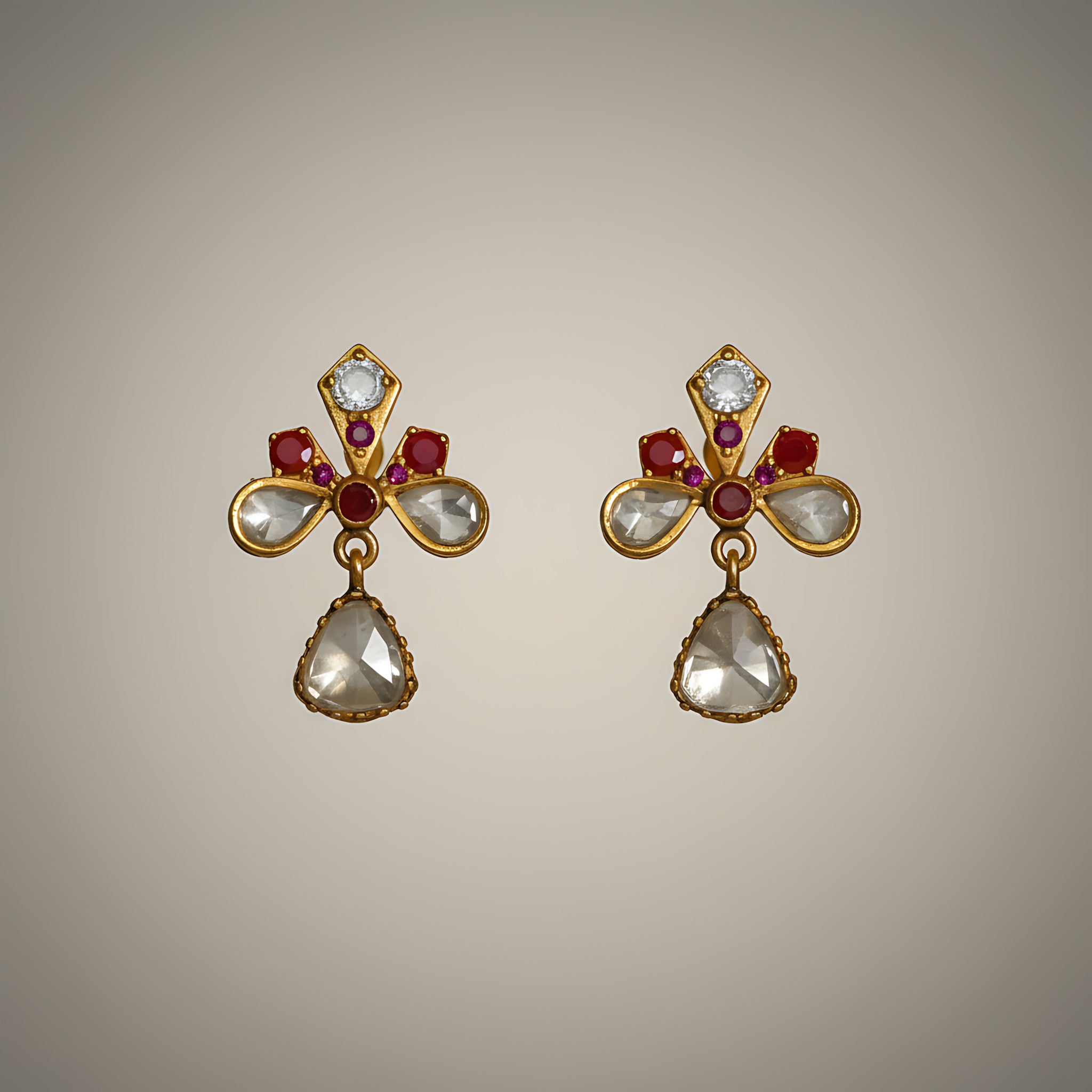 Pair of gold plated silver earrings with gemstones on a beige background