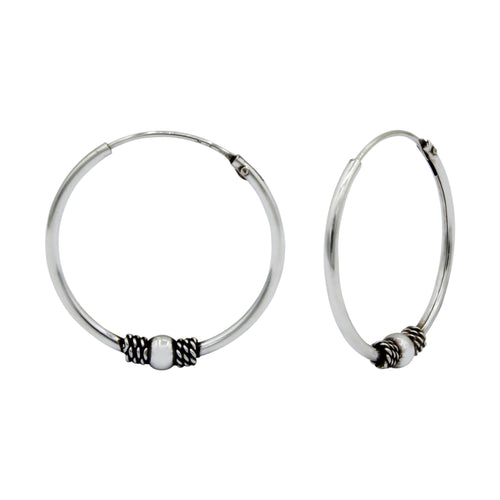 Pair of oxidized silver Bali hoop earrings with bead accents on a white background