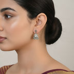 Close-up of a woman wearing an oxidized silver jhumka earring with a neutral background