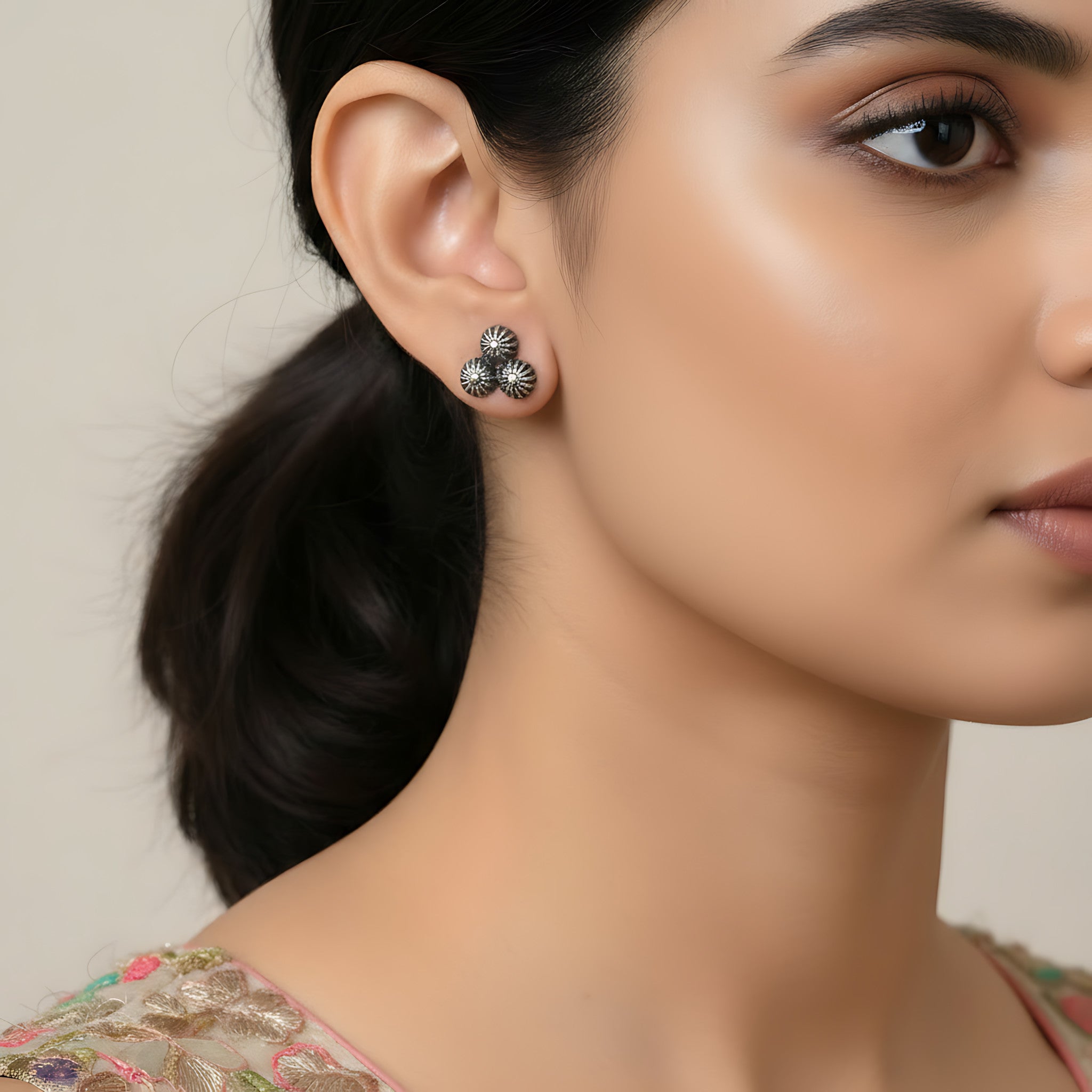 Close-up of a woman wearing a pair of 2 dome shaped oxidized silver earring with a neutral background