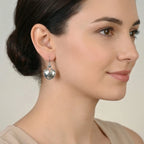 Woman wearing a shield shaped oxidized silver earring with a neutral background