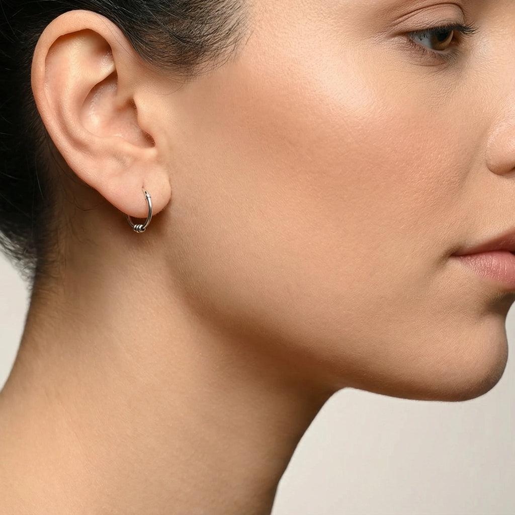 Close-up of a woman wearing a Oxidized Silver Triple Bead Bali Hoop Earring on a neutral background