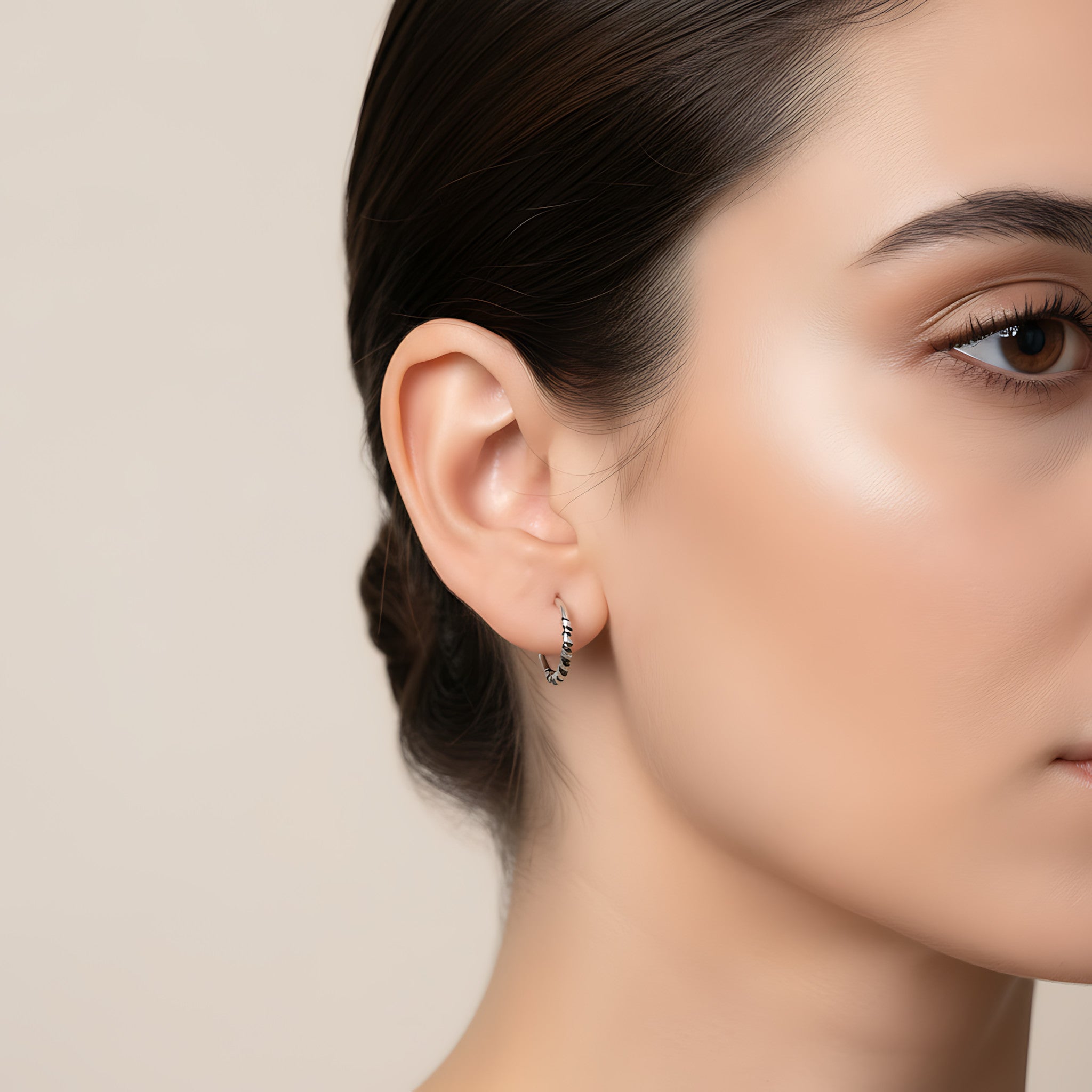 Close-up of a woman wearing a Bali half hoop stud earring against a neutral background