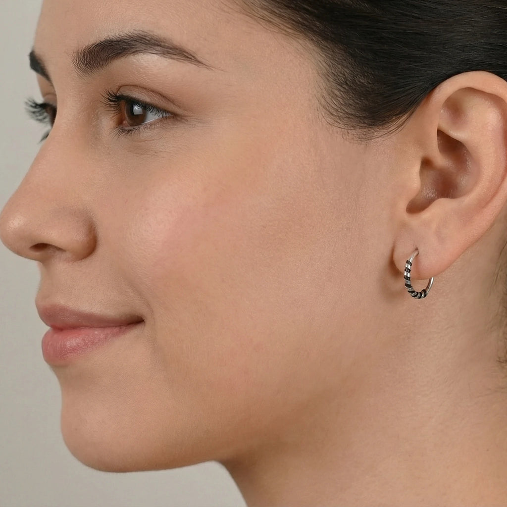 Close-up of a woman wearing a Bali half hoop stud earring against a neutral background
