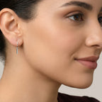 Close-up of a woman wearing a silver bar charm hoop earring