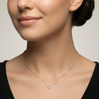 Closeup of a female wearing a silver necklace with a small butterfly pendant against a neutral background