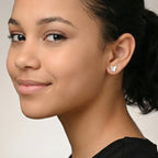 Close-up of a young girl wearing silver butterfly stud earrings against a neutral background