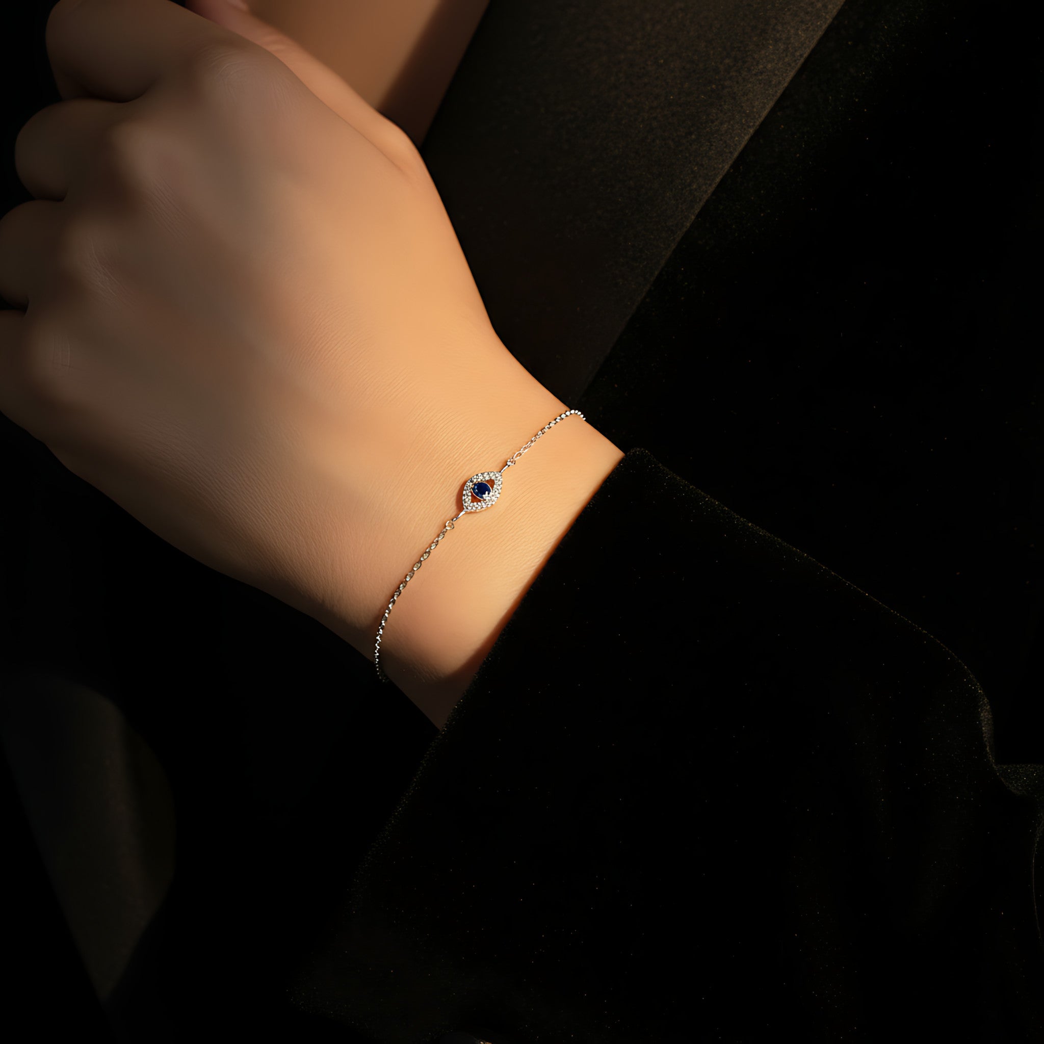 A female hand wearing a silver evil eye bracelet and female is wearing a black blazer