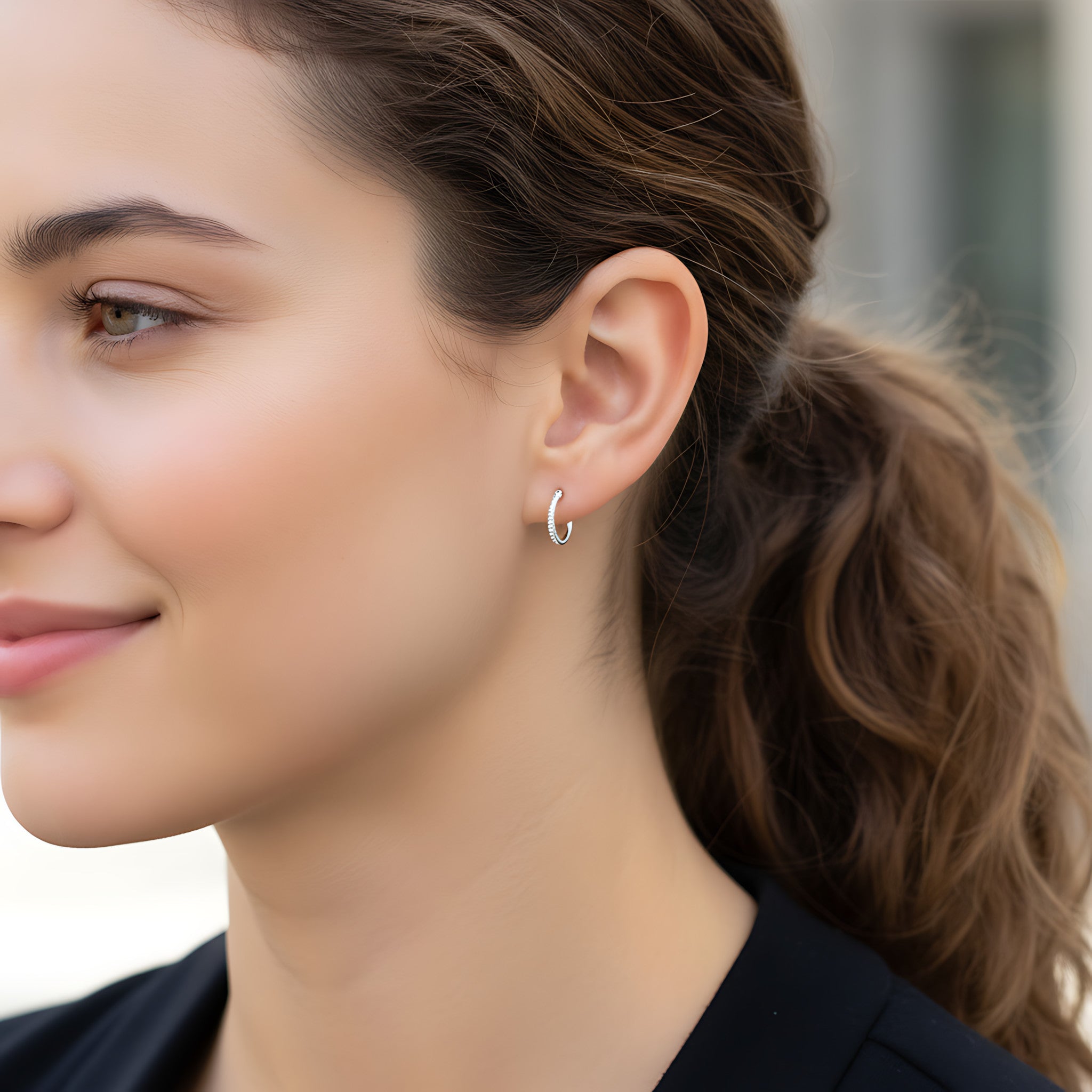 Close-up of a woman wearing a CZ French lock silver hoop earring with a blurred background