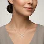 Woman wearing a delicate silver necklace with a small horseshoe pendant against a neutral background