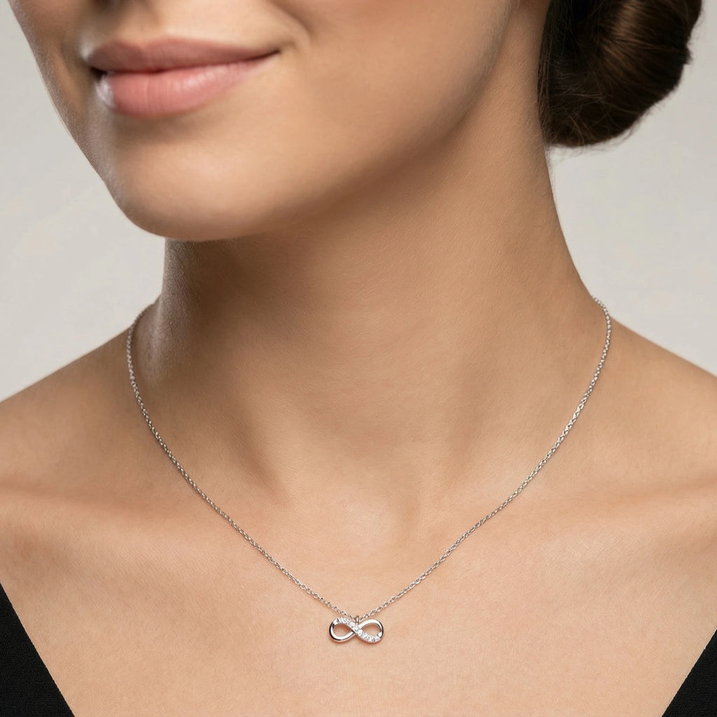 Woman wearing a silver necklace with an infinity symbol on a neutral background