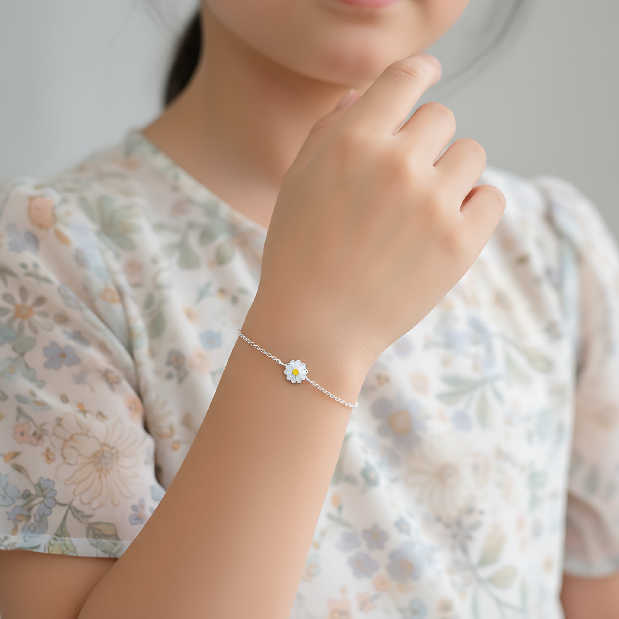 A girl wearing a silver flower bracelet and a blue floral dress against a light background