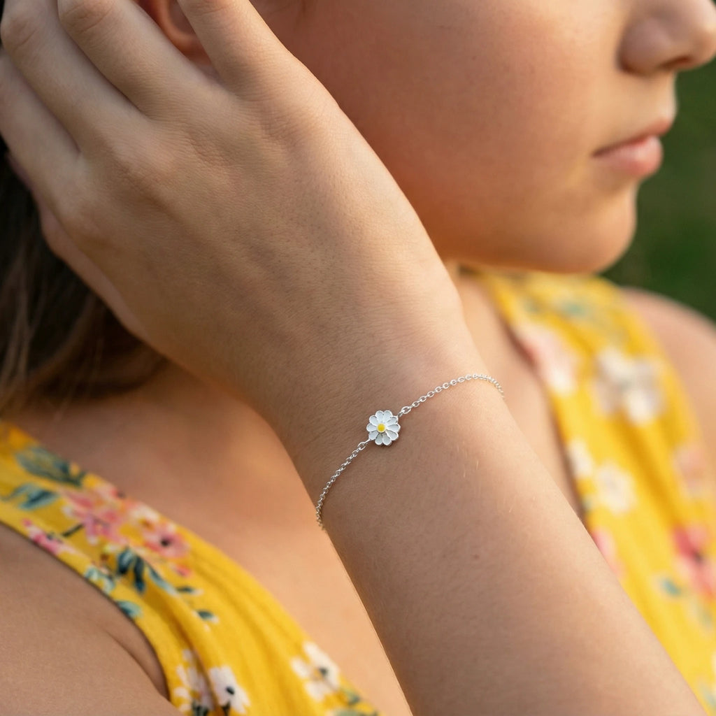 A girl wearing a silver daisy flower bracelet and a yellow floral dress outdoors