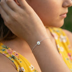 A girl wearing a silver daisy flower bracelet and a yellow floral dress outdoors