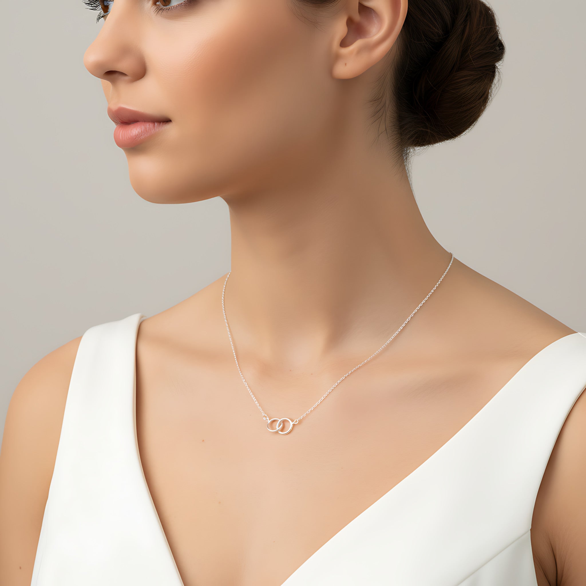 Woman wearing a delicate necklace with interlocking rings on a neutral background