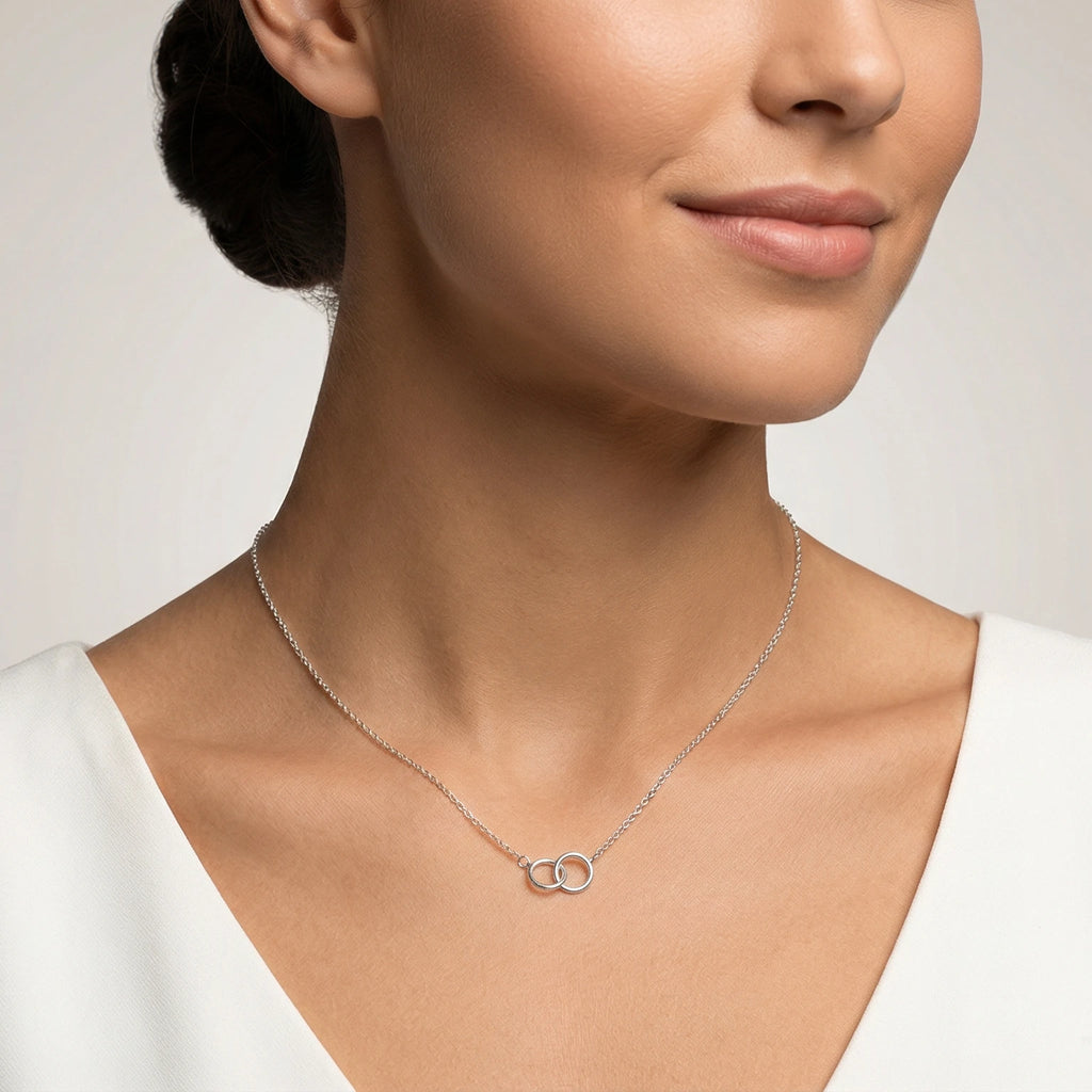Woman wearing a delicate necklace with interlocking rings on a neutral background