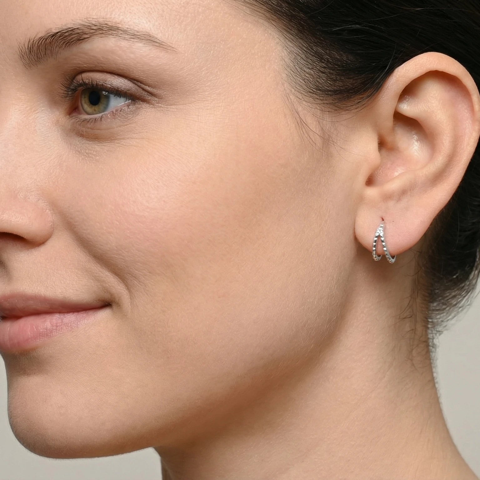 Close-up of an ear wearing a double spiked silver hoop earring