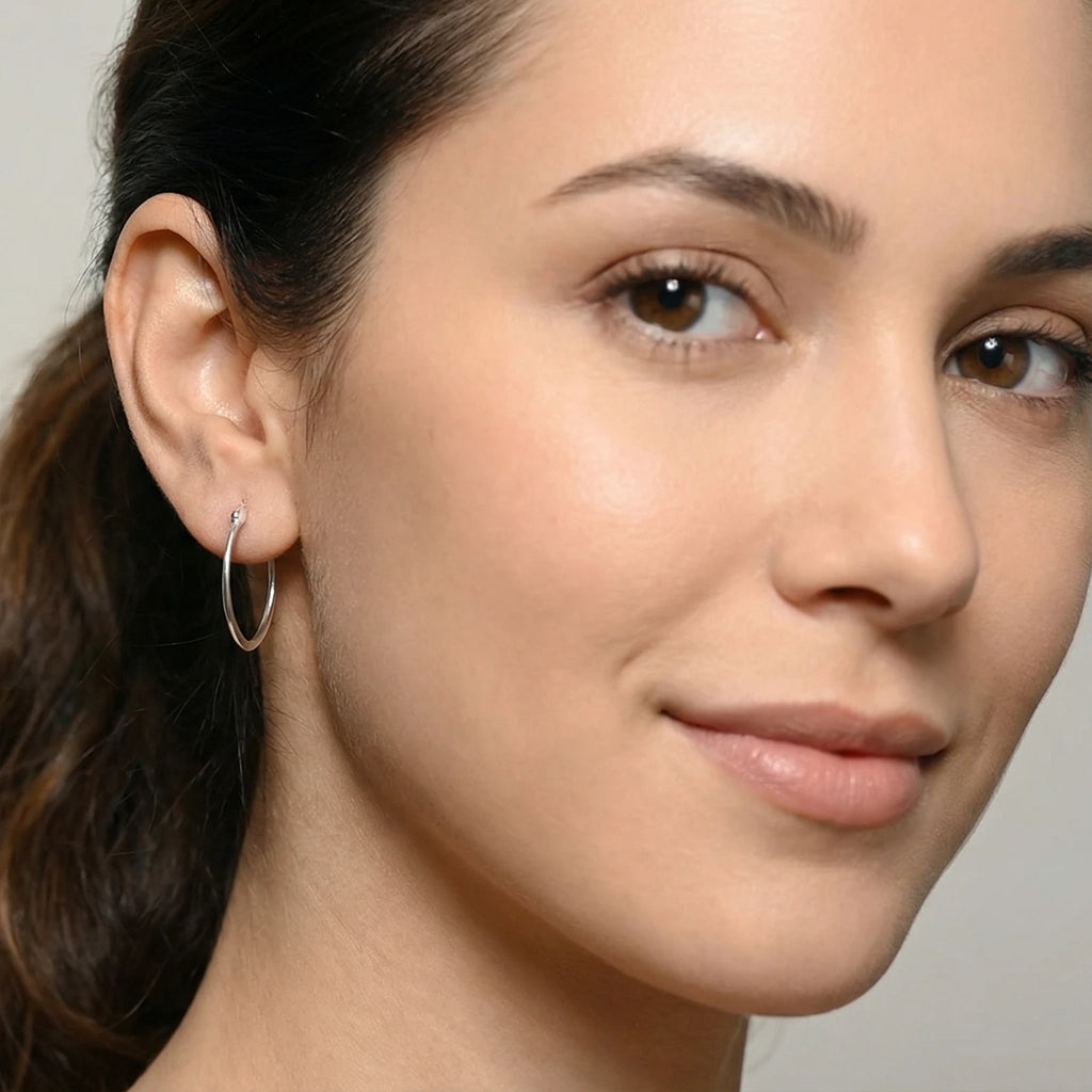 Close-up of a woman wearing a Silver Elongated Oval French Lock Hoop Earring  with a neutral background