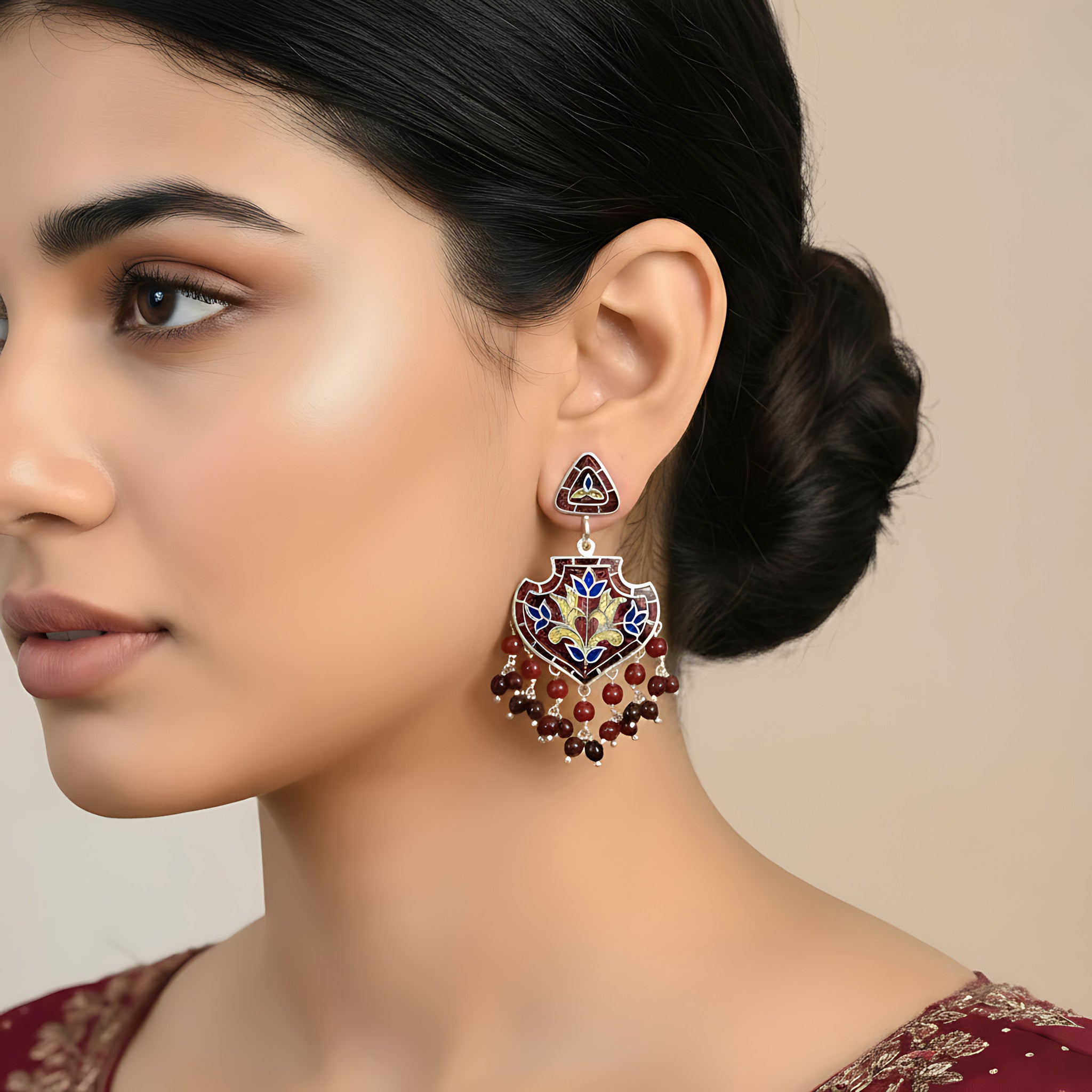 Woman wearing a decorative red-gold silver enamel earring with a neutral background