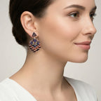 Woman wearing a decorative red-gold silver enamel earring with a neutral background