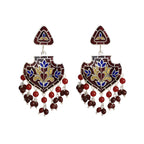 Pair of decorative enamel silver earrings with intricate designs in red, gold and blue colours on a white background
