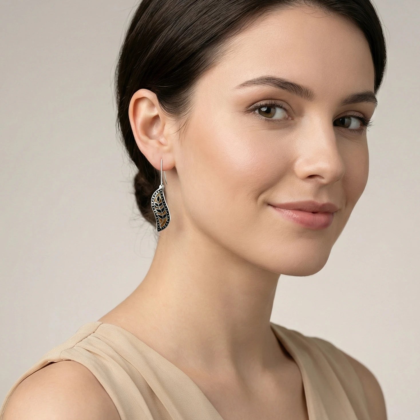 Woman wearing black-gold meenakari earrings with a neutral background
