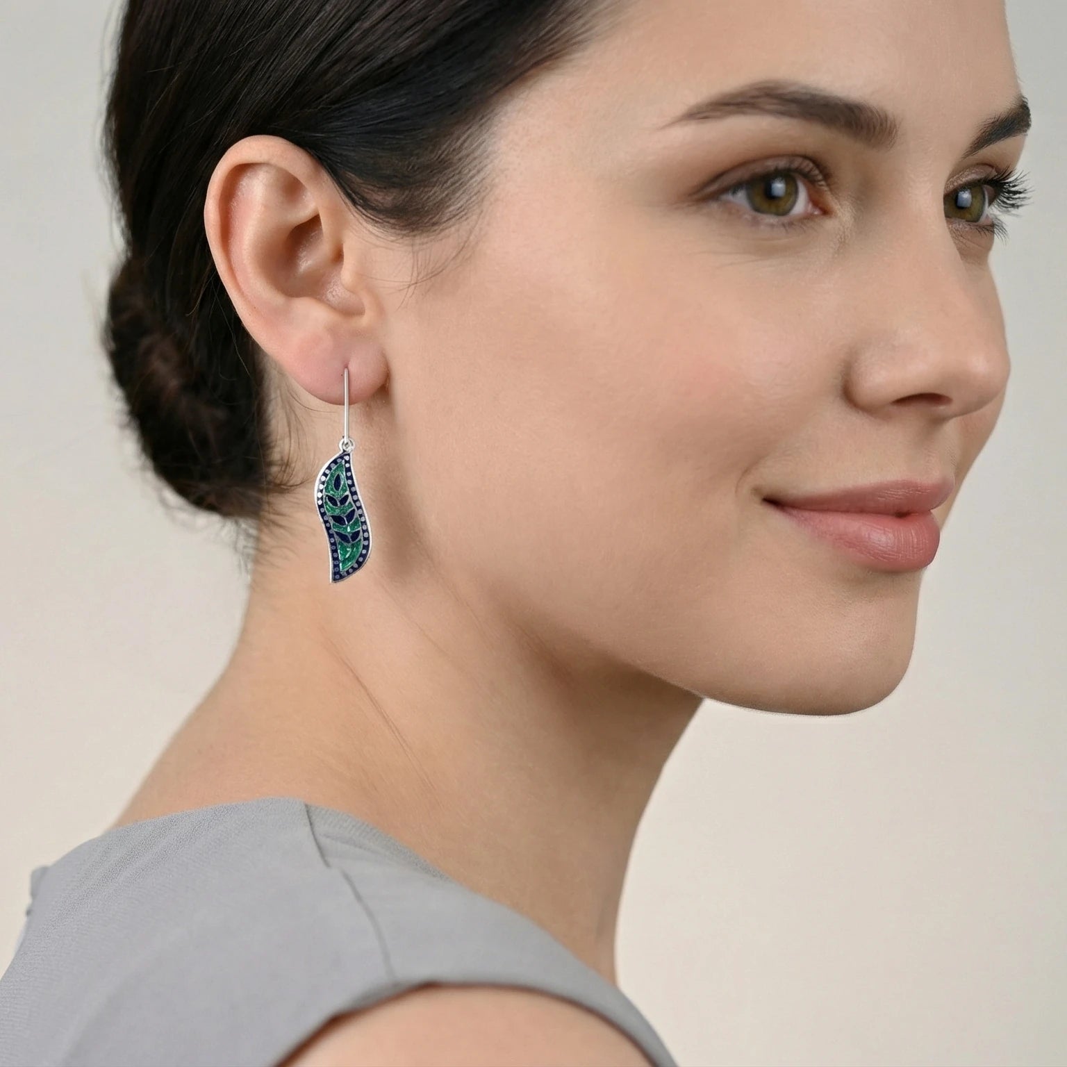 Woman wearing blue-green meenakari earrings with a neutral background