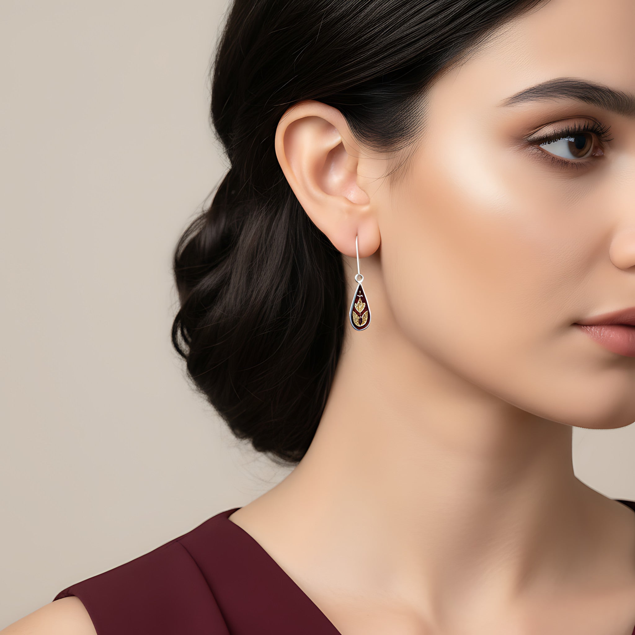 Close-up of a woman wearing a droplet shaped silver enamel earring against a neutral background