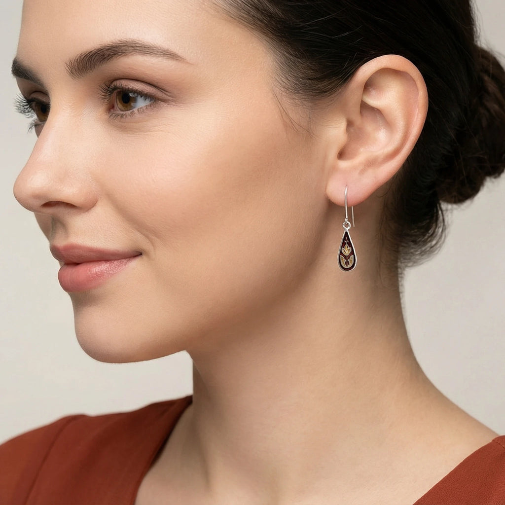 Close-up of a woman wearing a droplet shaped silver enamel earring against a neutral background