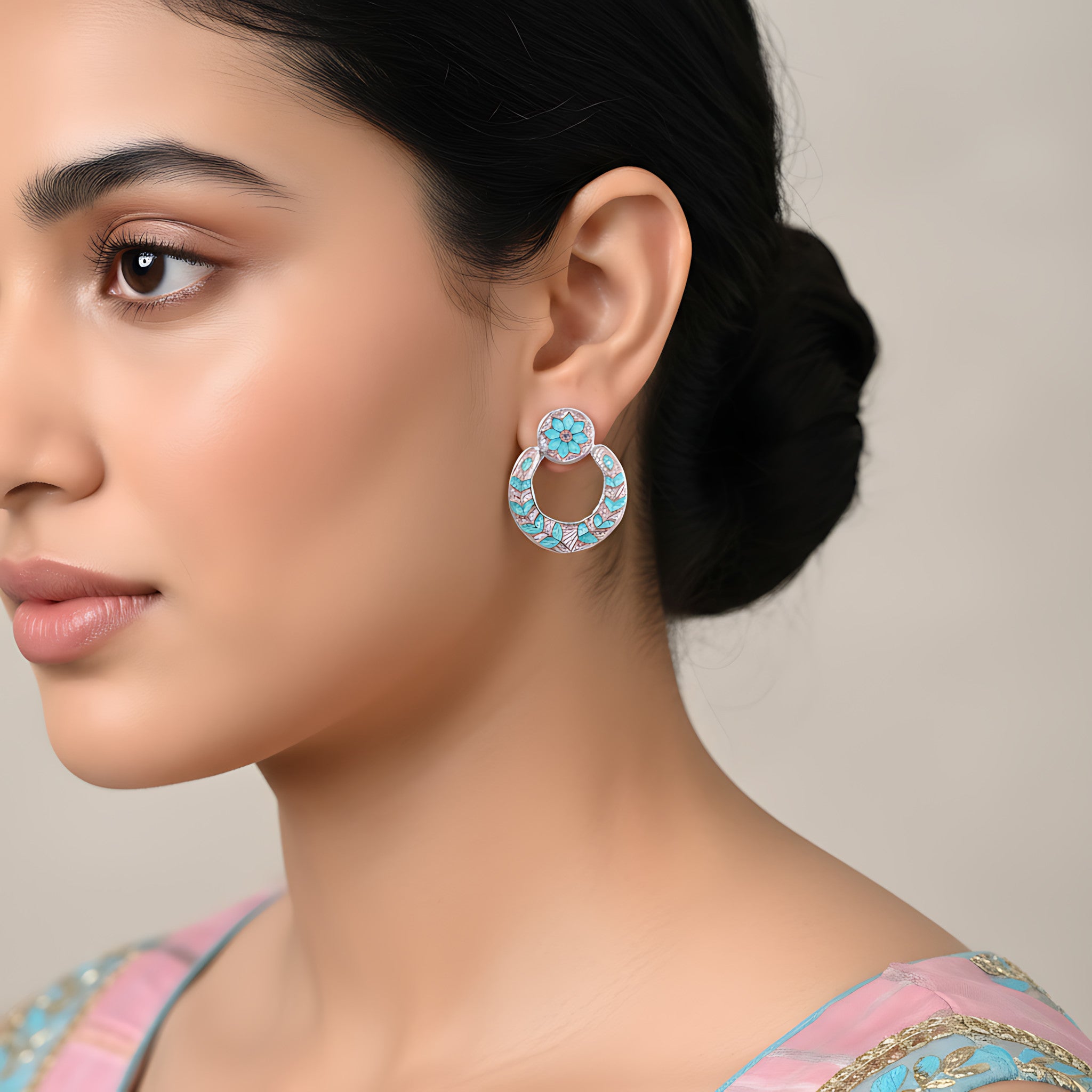 Close-up of a woman wearing a decorative pink-blue silver enamel  earring with a neutral background