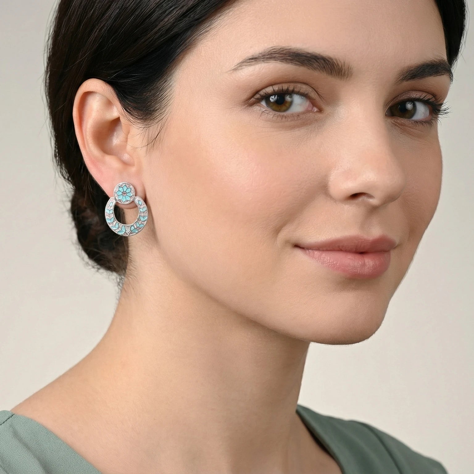 Close-up of a woman wearing a decorative pink-blue silver enamel  earring with a neutral background