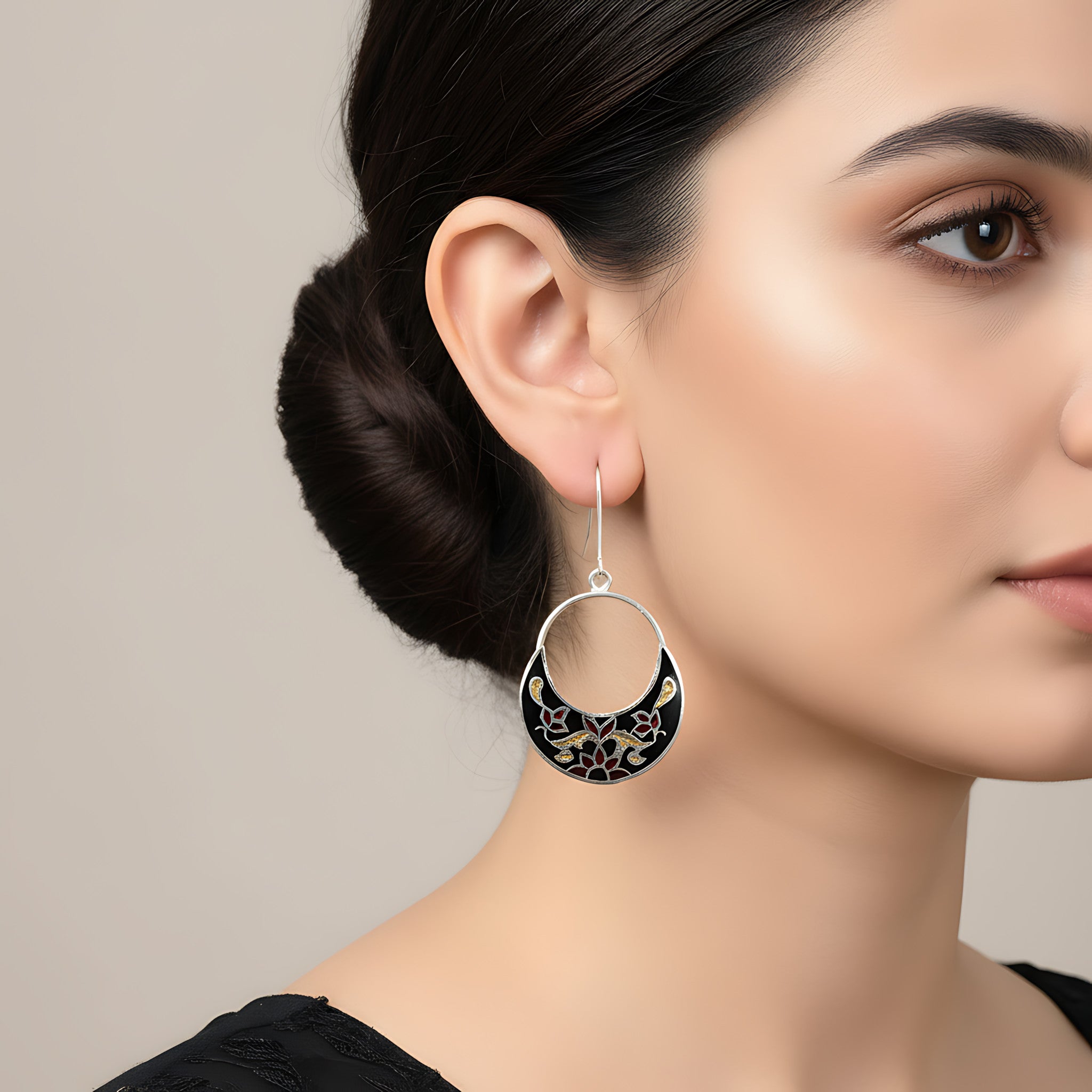 Close-up of a woman wearing a black-gold silver enamel earring against a neutral background