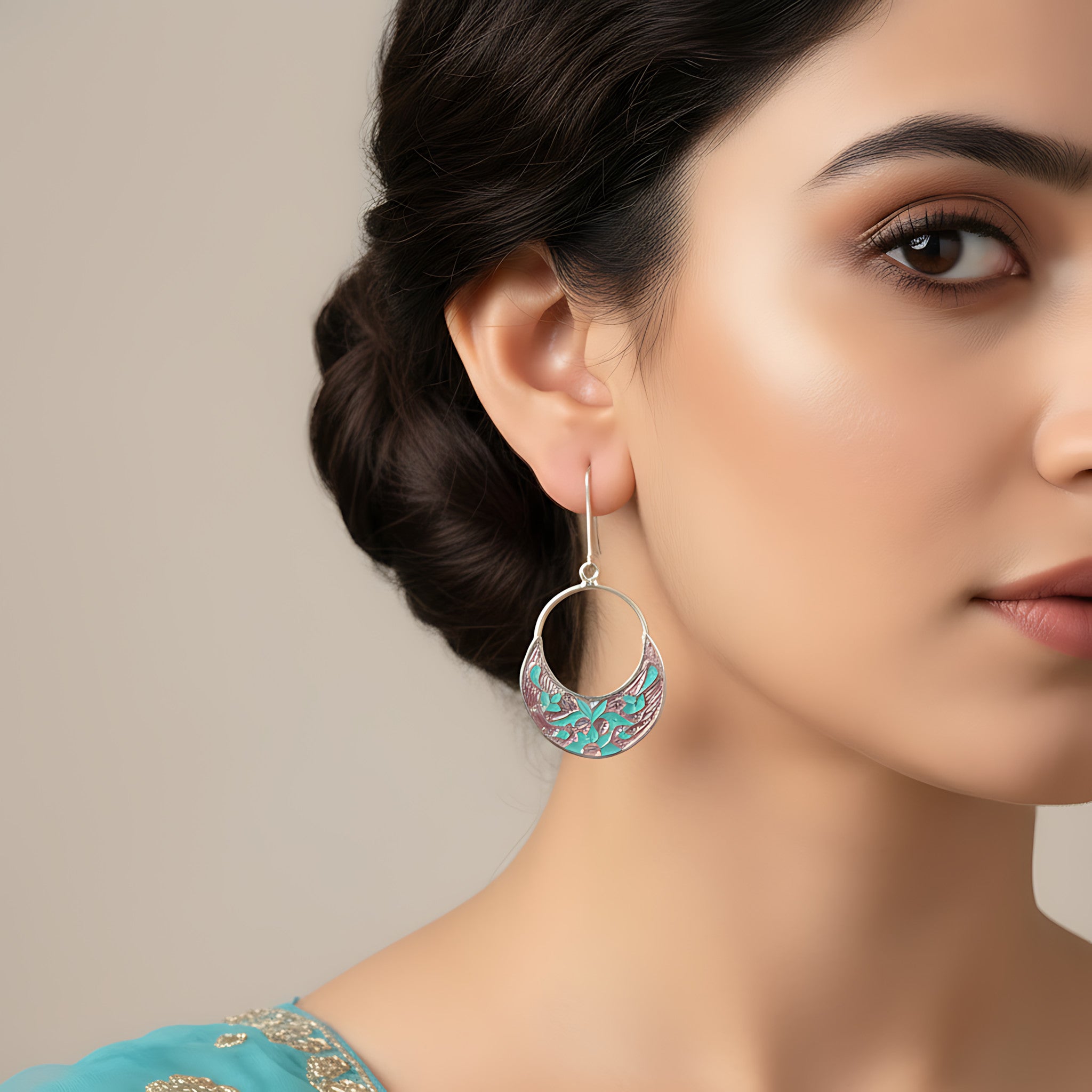 Close-up of a woman wearing a pink-turquoise silver enamel earring against a neutral background