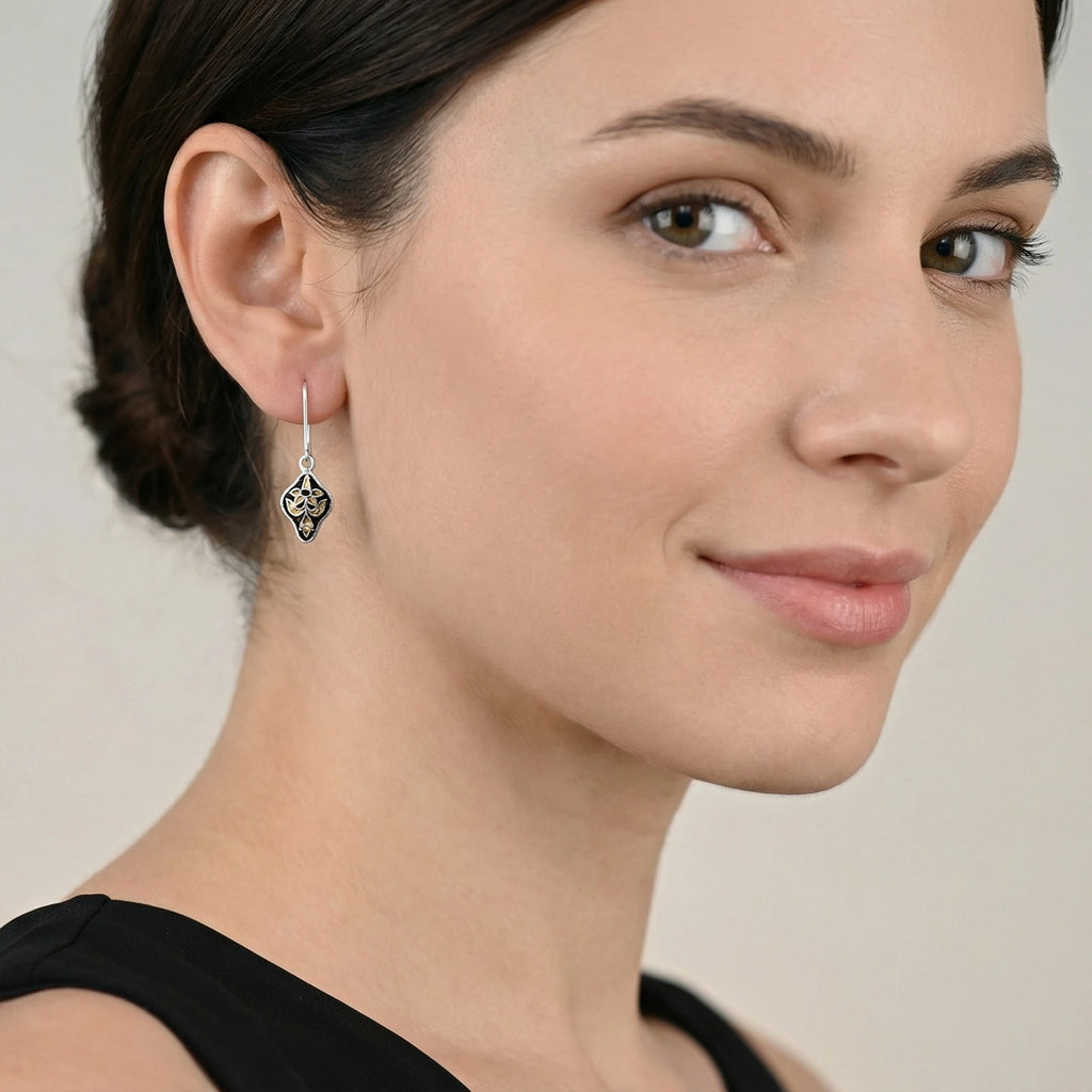 Close-up of a woman wearing a dark maroon and golden silver enamel earring against a neutral background