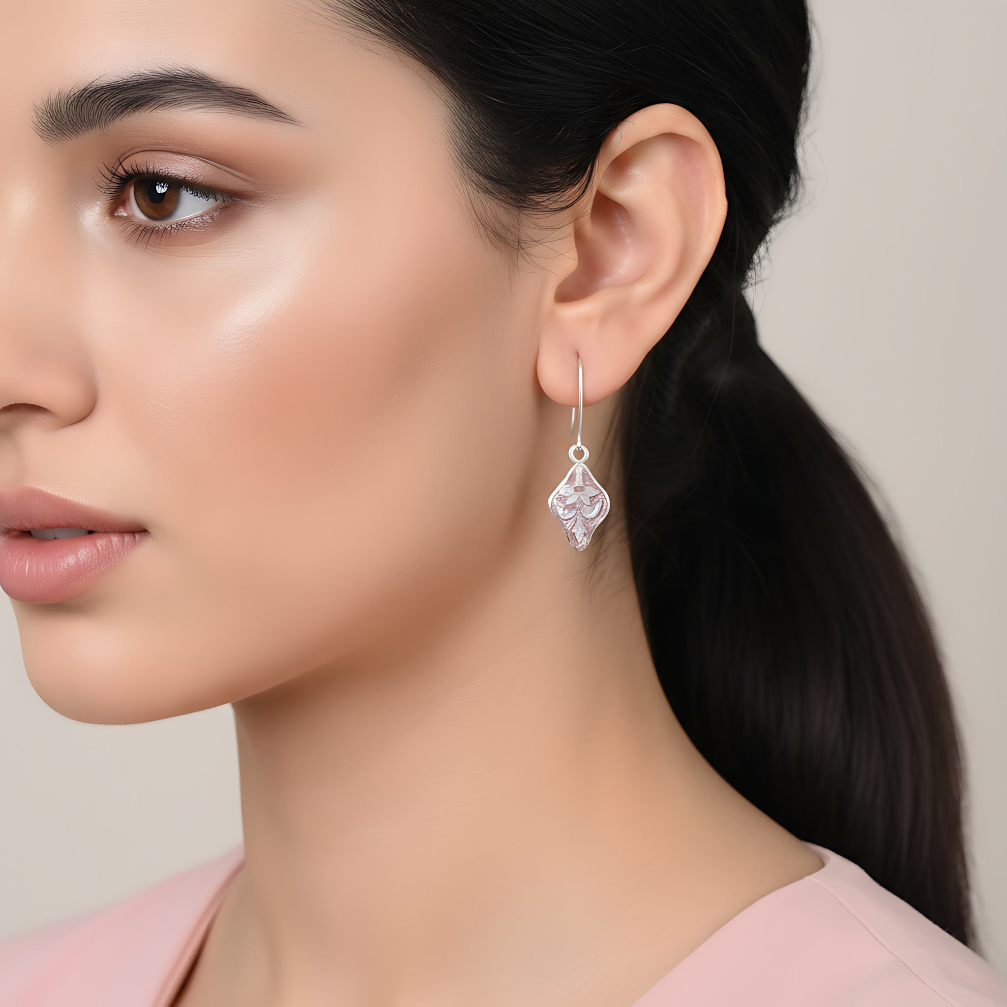 Close-up of a woman wearing a pink enamel silver earring with a neutral background