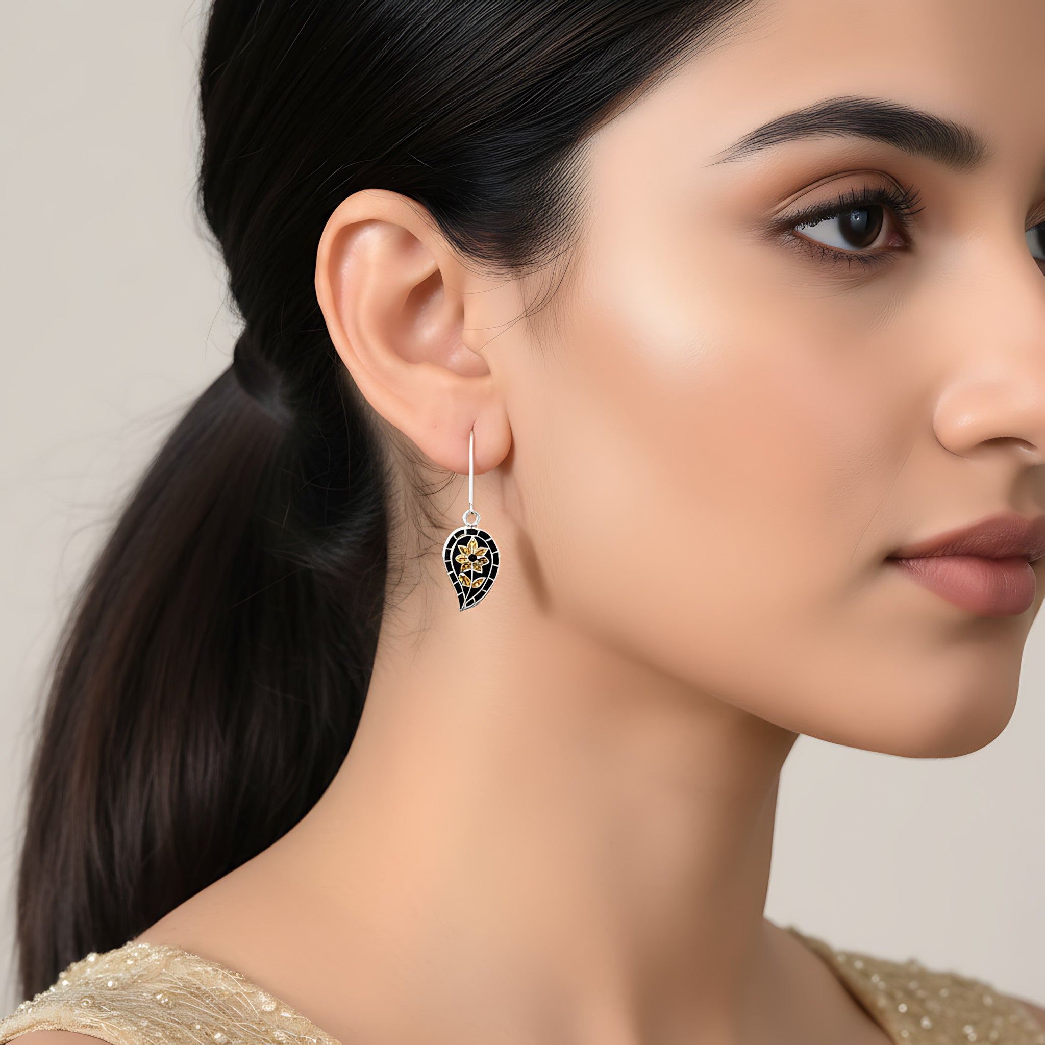 Woman wearing a black-gold silver enamel earring with a neutral background