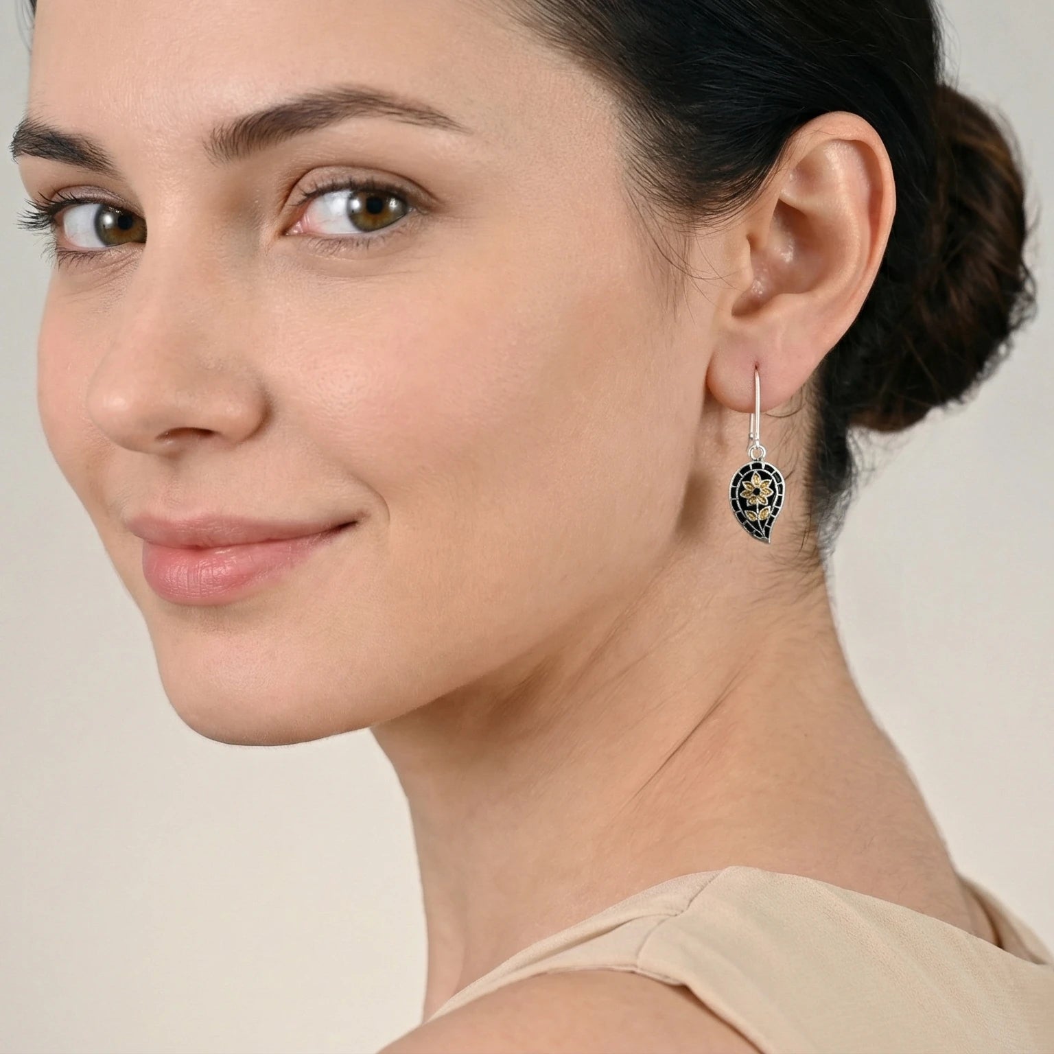 Woman wearing a black-gold silver enamel earring with a neutral background