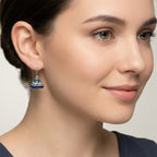 Close-up of a woman wearing a silver jhumka earring with blue enamel work.