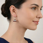 Close-up of a woman wearing a silver jhumka earring with maroon enamel work.