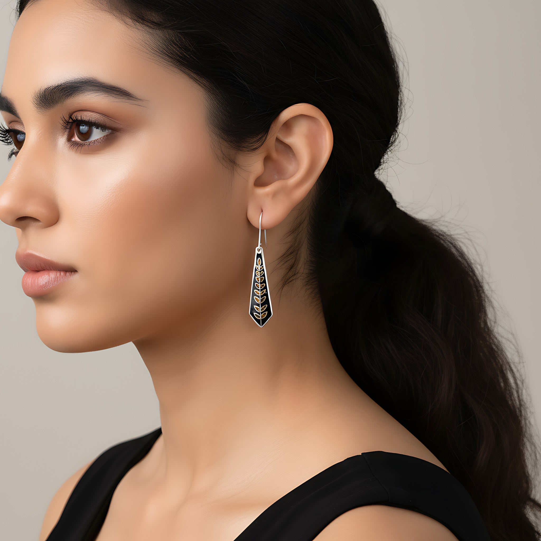 Woman wearing a black-gold silver enamel earring against a neutral background